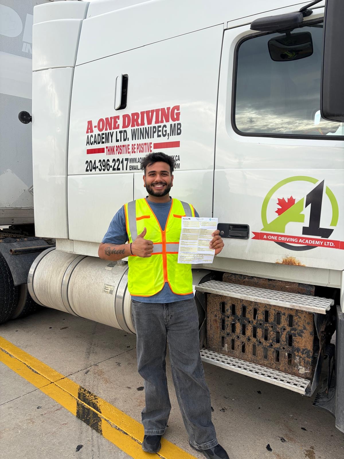 Student holding MPI road test pass certificate in front of A-One truck