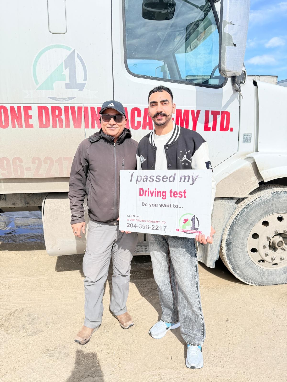 Instructor and student holding I passed my driving test sign in front of A-One truck