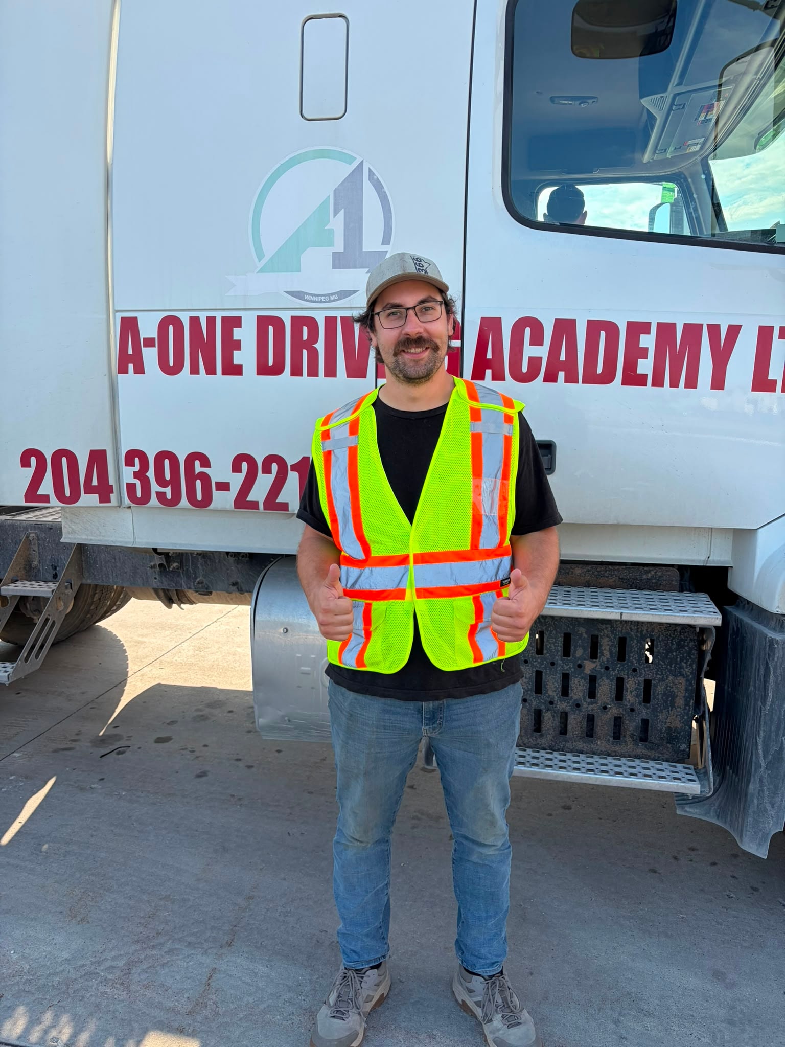 Student in safety vest giving thumbs up in front of A-One truck