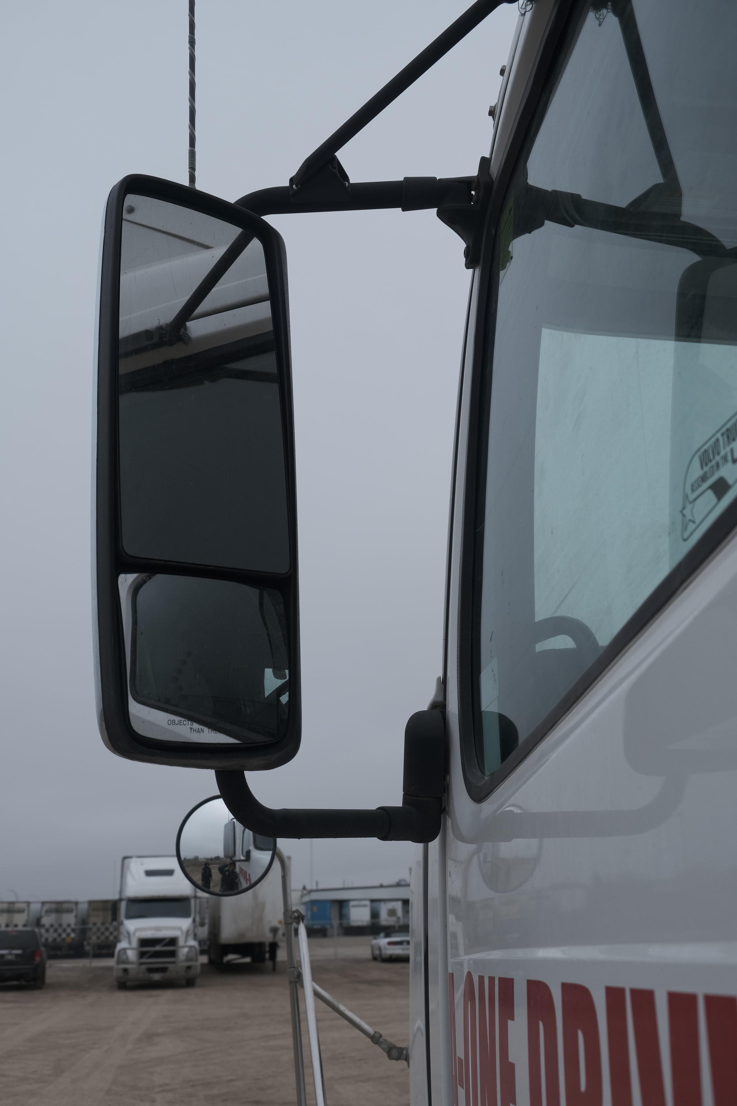 Close-up of commercial truck cab mirror and windshield